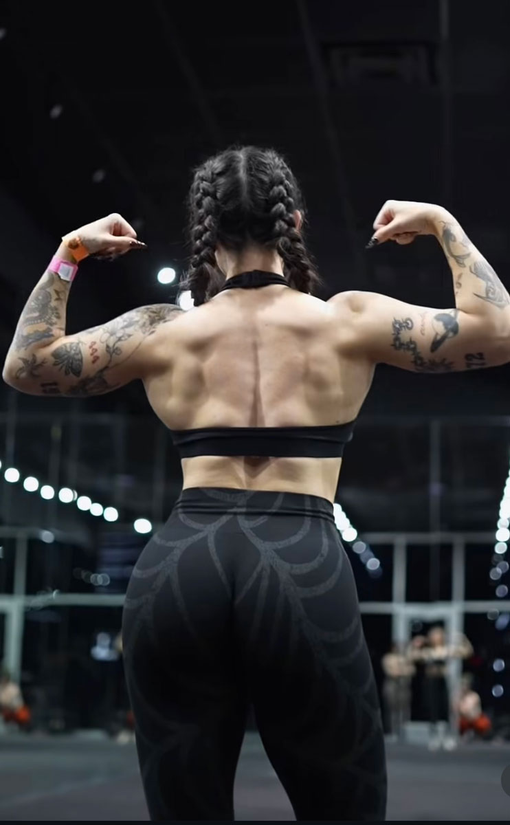 The coach is back posing to show her back muscle.